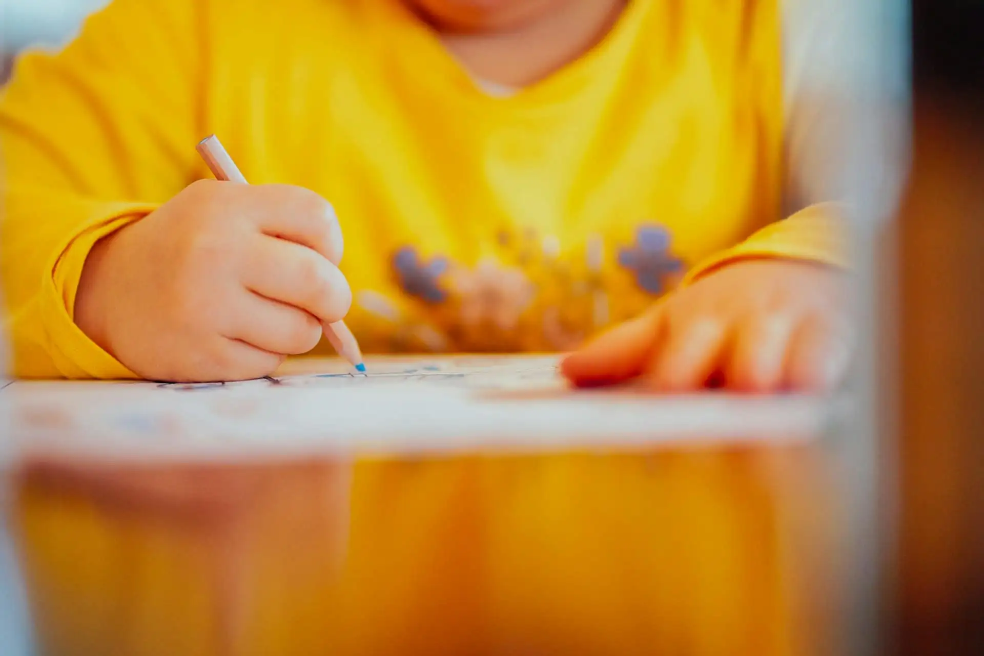 Child writing letters in a notebook with a pencil